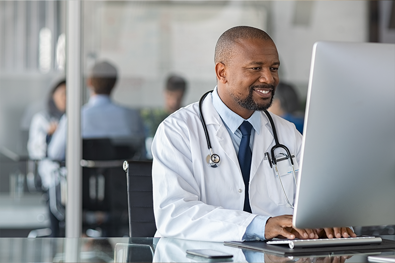 Male doctor sitting at laptop computer