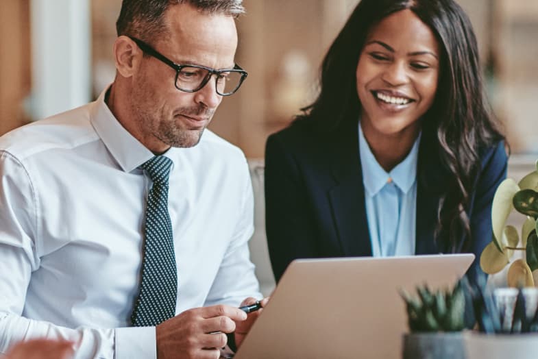 two office colleagues sitting at laptop smiling