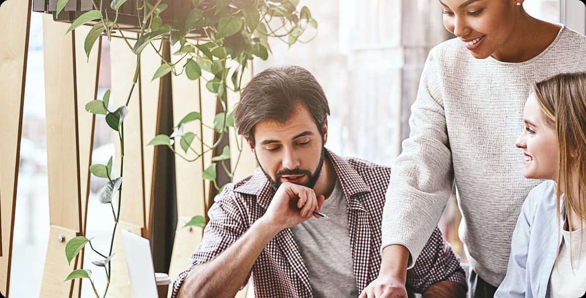 team in office setting standing and sitting around table talking