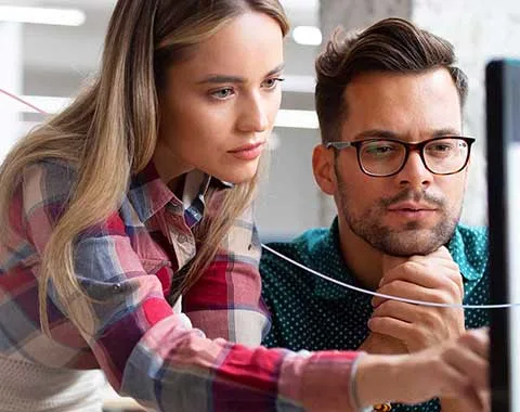 Coworkers focused intently on laptop screen
