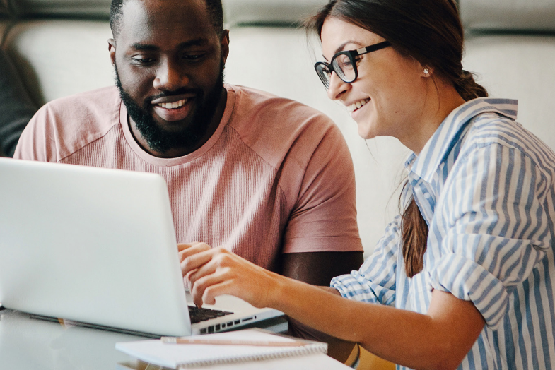 Pair of coworkers sitting and working together at laptop