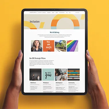 Person holding tablet viewing Land O' Lakes Phenom Career Site against a honey yellow background. 