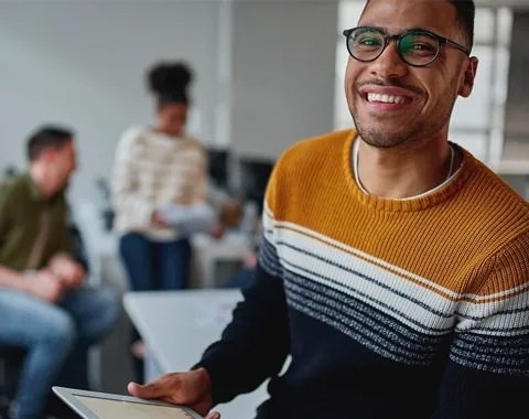 Young man on tablet in office setting smiling