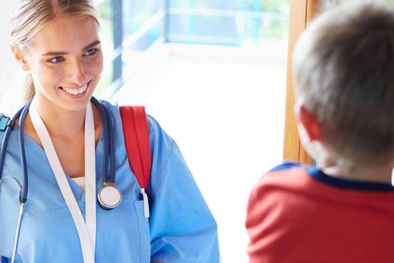 healthcare worker in scrubs sitting with pediatric patient