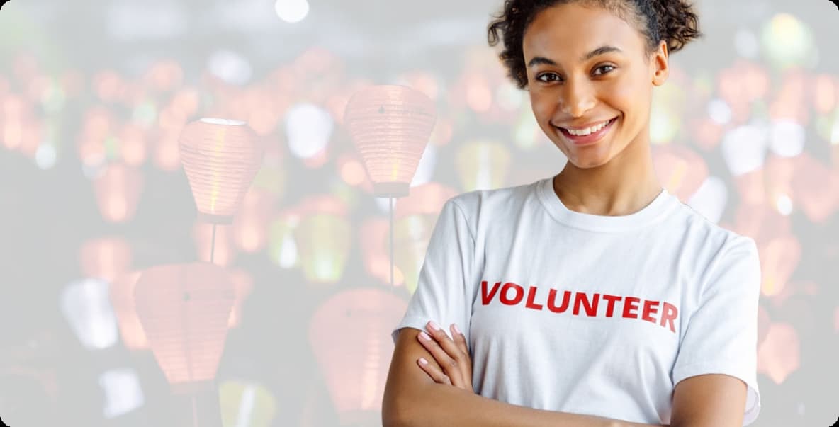 young woman smiling at camera with arms crossed wearing "Volunteer" t-shirt