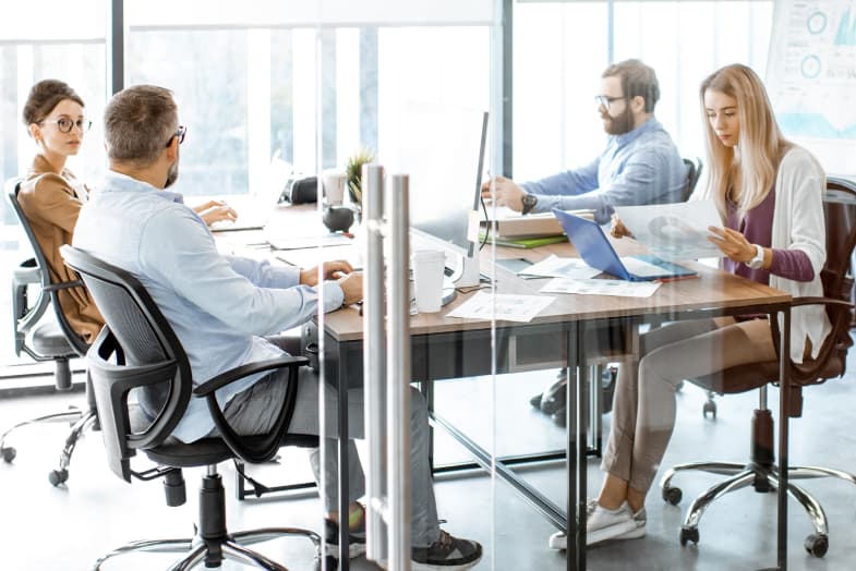 four coworkers in an office conference room sitting at conference table in a meeting