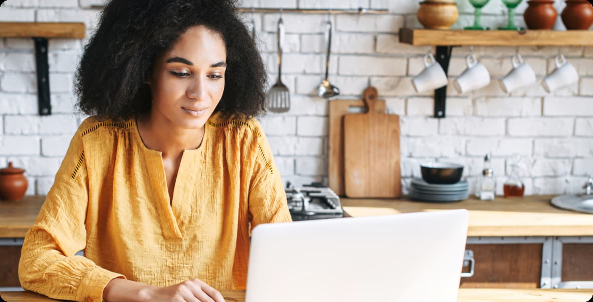 women sitting in kitchen on her laptop