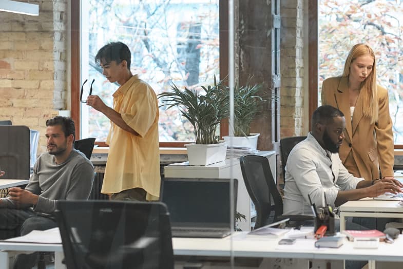 Office setting, open, casual with team members collaborating at desks