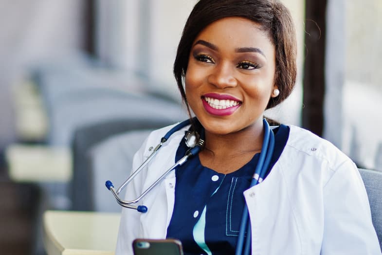 Young medical professional sitting in chair with smartphone smiling