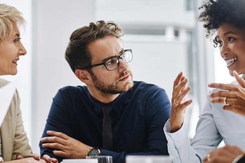 office coworkers sitting at table smiling mid-discussion