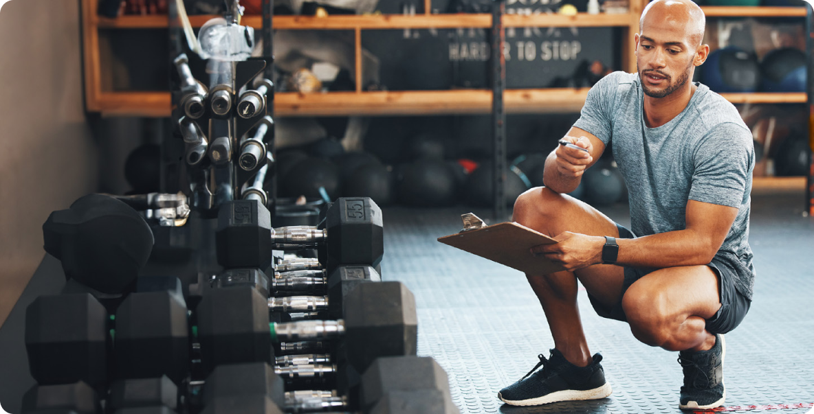 man in workout gear looking at weights set in gym