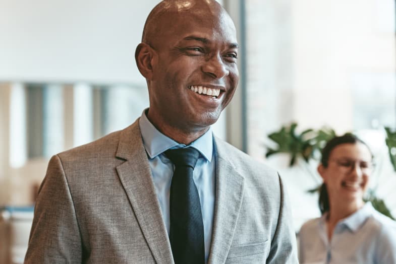 older man in formal office attire and setting smiling