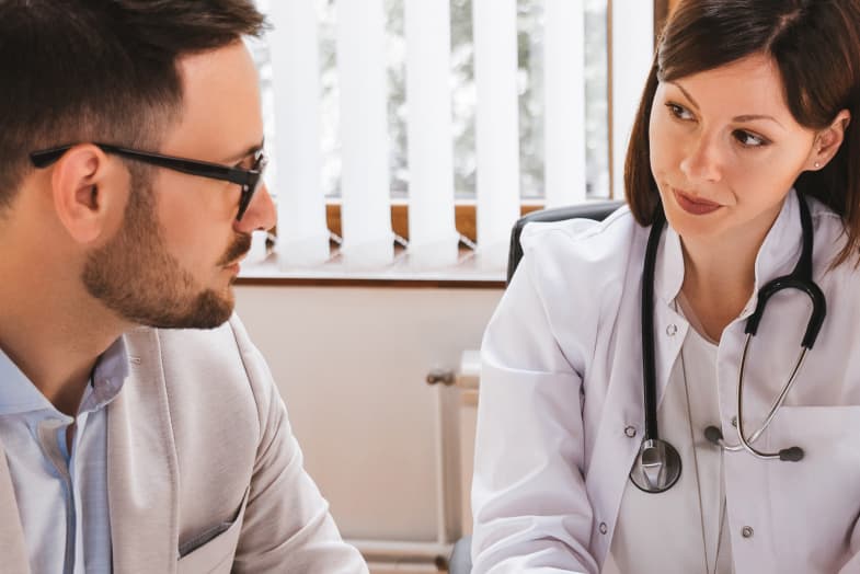 female doctor sitting with male in suit and glasses