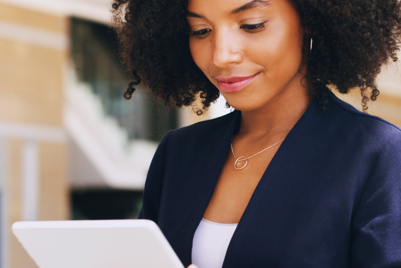 Young woman in business suit smiling at tablet screen