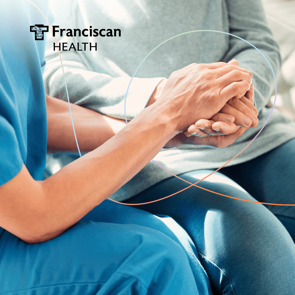 A nurse holding an elderly patient's hands.