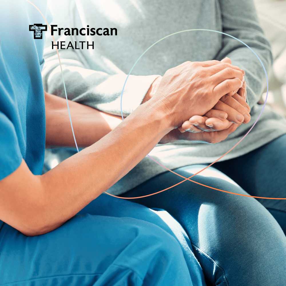 A nurse holding an elderly patient's hands.