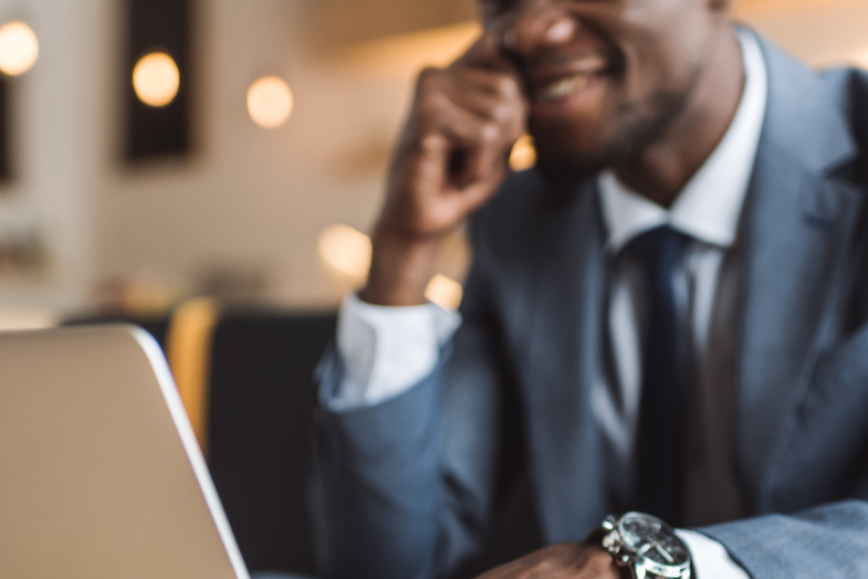 Man in business suit smiling, out of focus working on computer