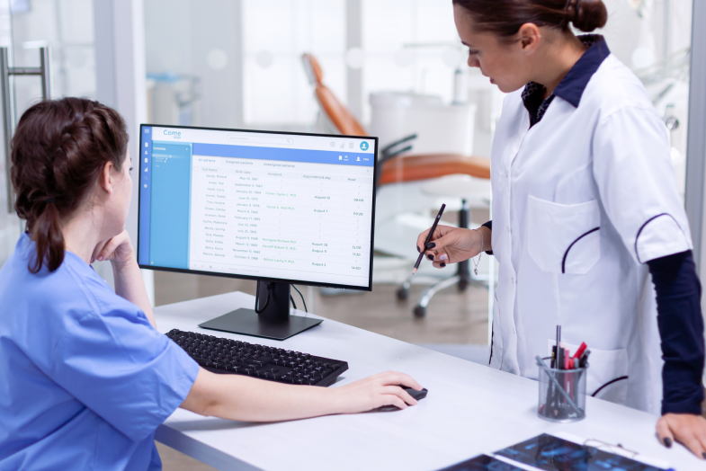 healthcare workers talking in front of desktop computer screen