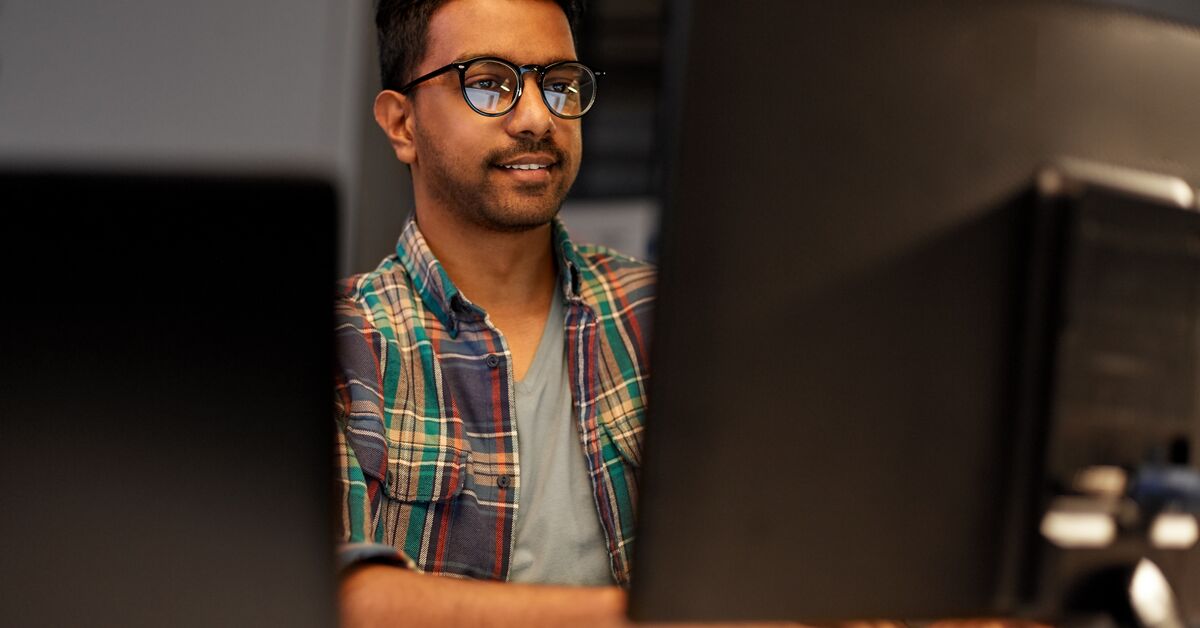 Young man working on two computer monitors