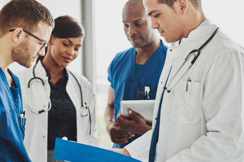 group of young healthcare professionals standing around in medical facility 