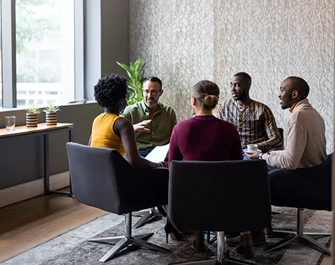 Group of diverse colleagues sitting at a table in deep conversation.