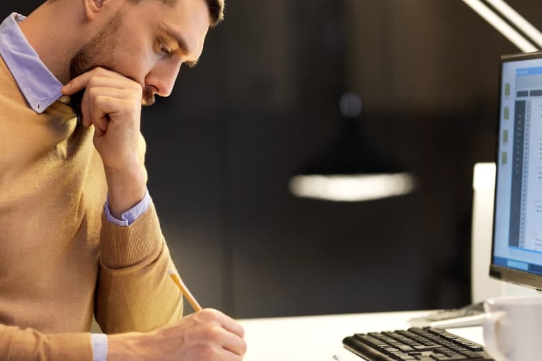 young man sitting at desktop looking concerned