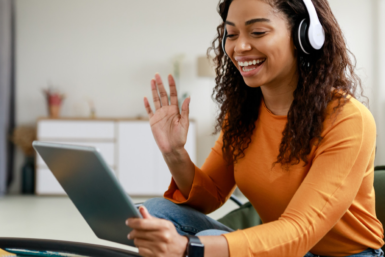 young woman with headphones on talking at tablet computer