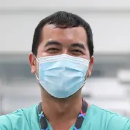 Image of man wearing facemask in a hospital, wearing NHS uniform