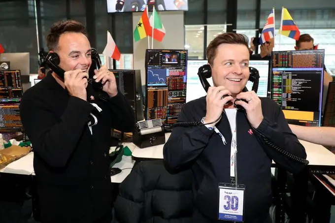 Image of Prince's Trust ambassadors Ant and Dec holding phones to their ears and smiling, as they raise money for The Prince's Trust at ICAP Charity Day