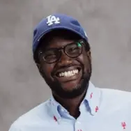 Image of young man wearing a baseball cap and smiling at the camera