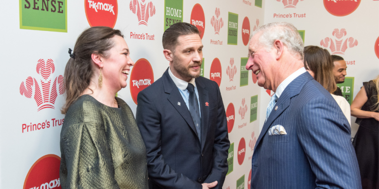 King Charles meeting Tom Hardy and Olivia Coleman at the Prince's Trust Awards event in front of a logo backboard