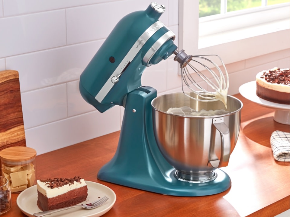 Stand-mixer-with-wire-whisk-and-stainless-steel-bowl-on-kitcehn-counter-with-cake