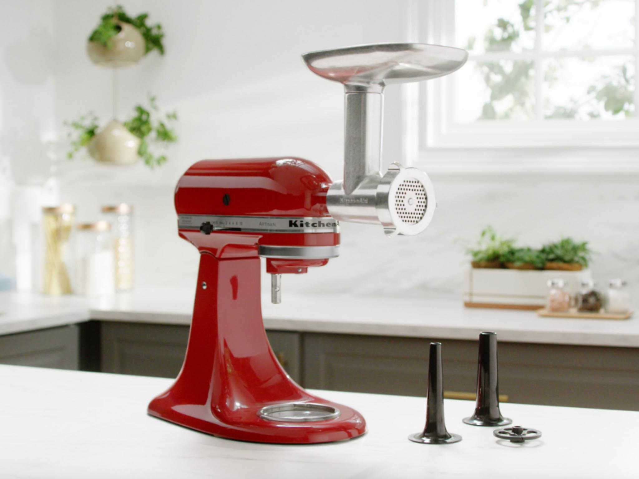 Stand-mixer-and-meat-grinder-attachment-and-sausage-stuffer-tubes-and-plate-on-kitchen-counter