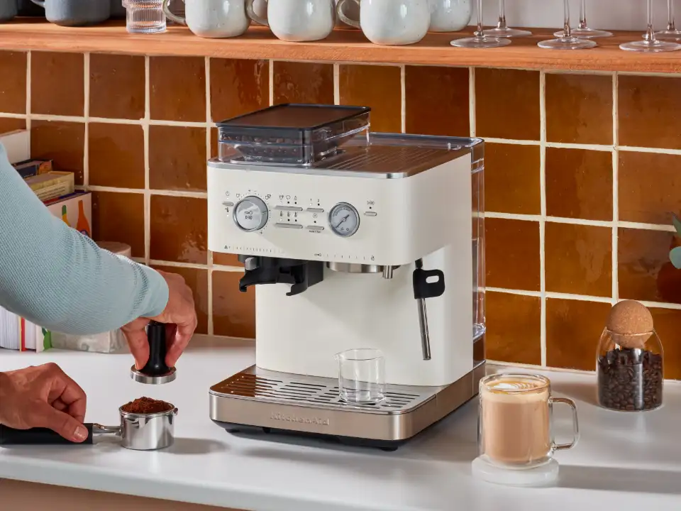 person-tamping-coffee-in-front-of-semi-automatic-coffee-machine-with-burr-grinder