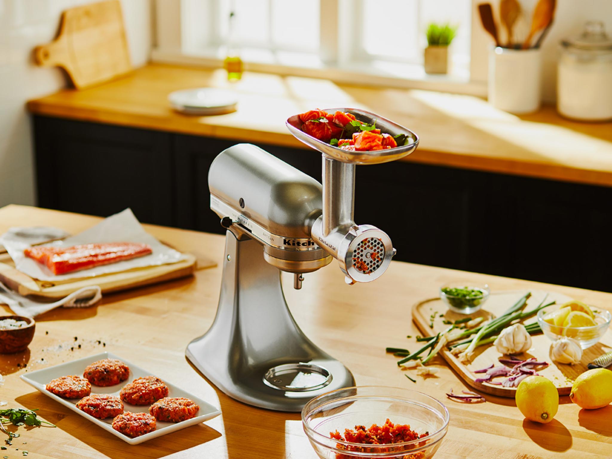 Stand-mixer-and-meat-grinder-and-sausage-stuffer-attachment-on-counter-with-ingrdients-and-raw-meatballs