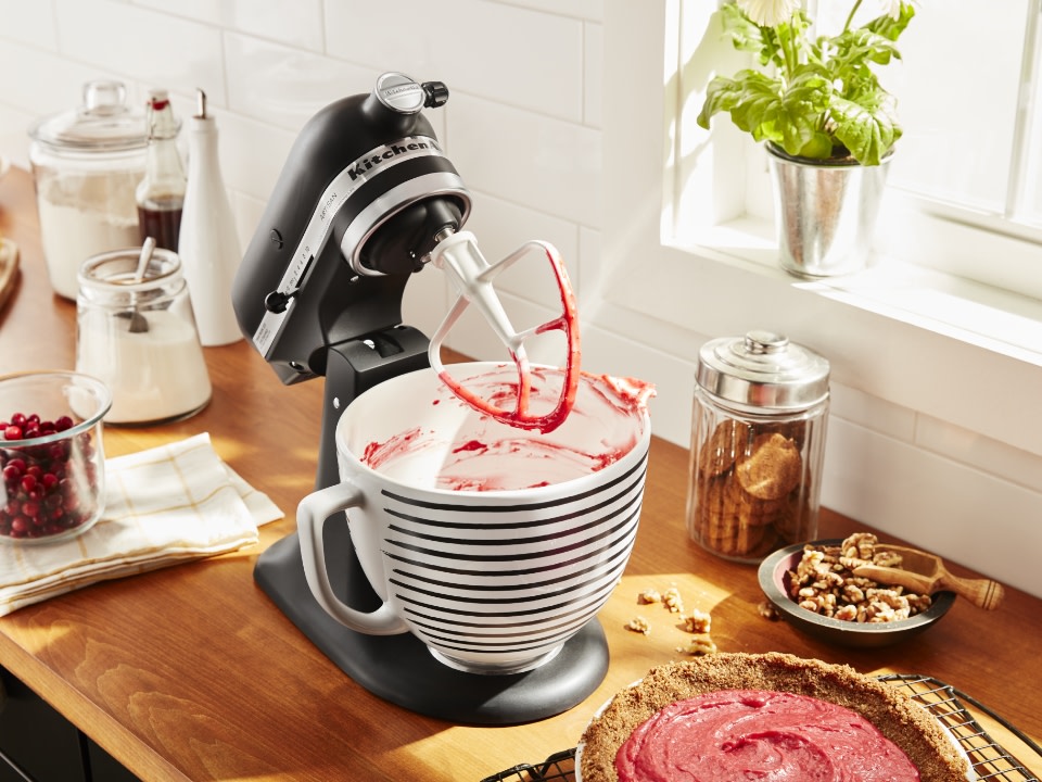 Tilt-head-stand-mixer-and-paddle-with-pink-icing-and-tart-on-a-counter