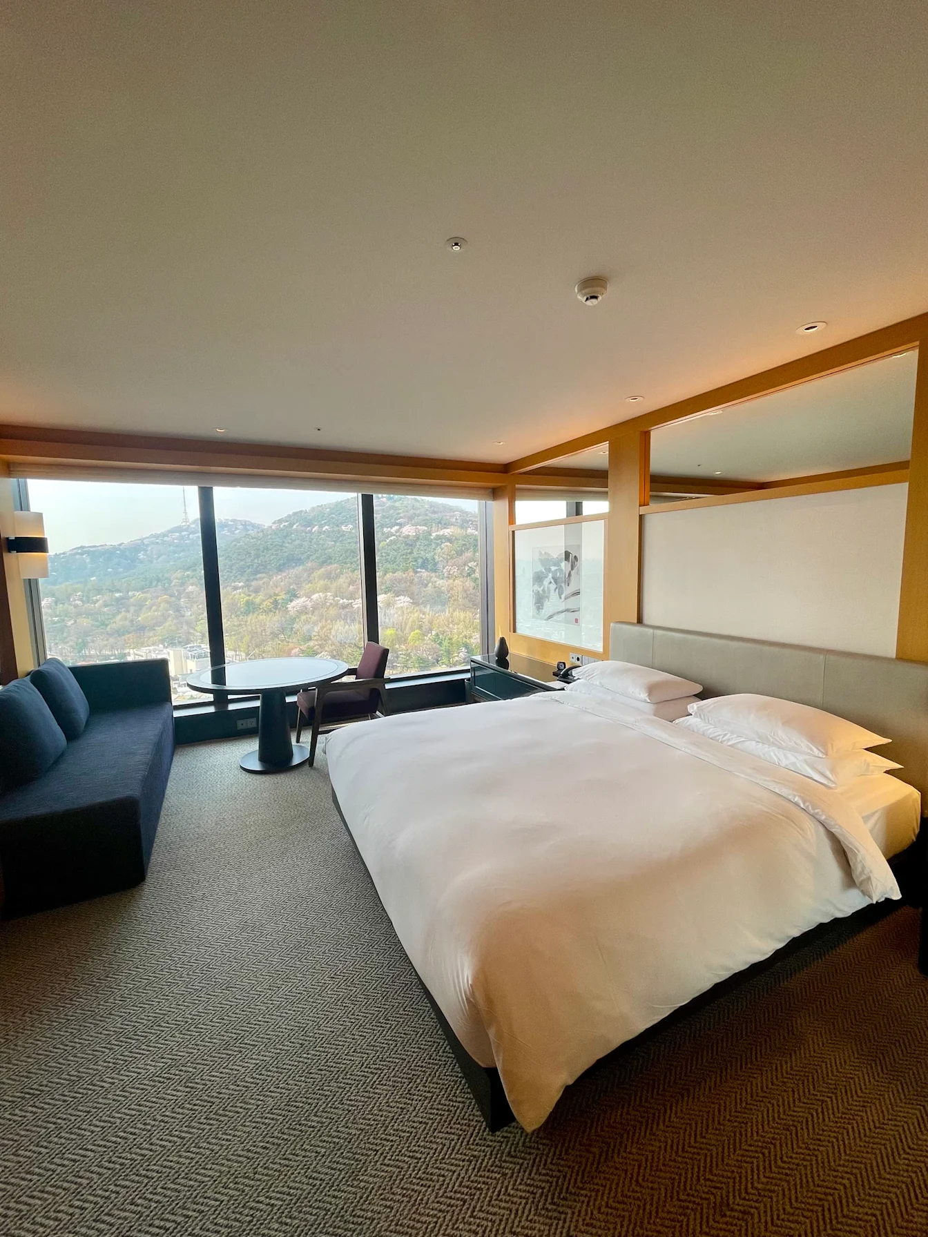 King Room với cửa kính lớn nhìn ra đồi Namsan, sofa và bàn nhỏ cạnh cửa sổ
