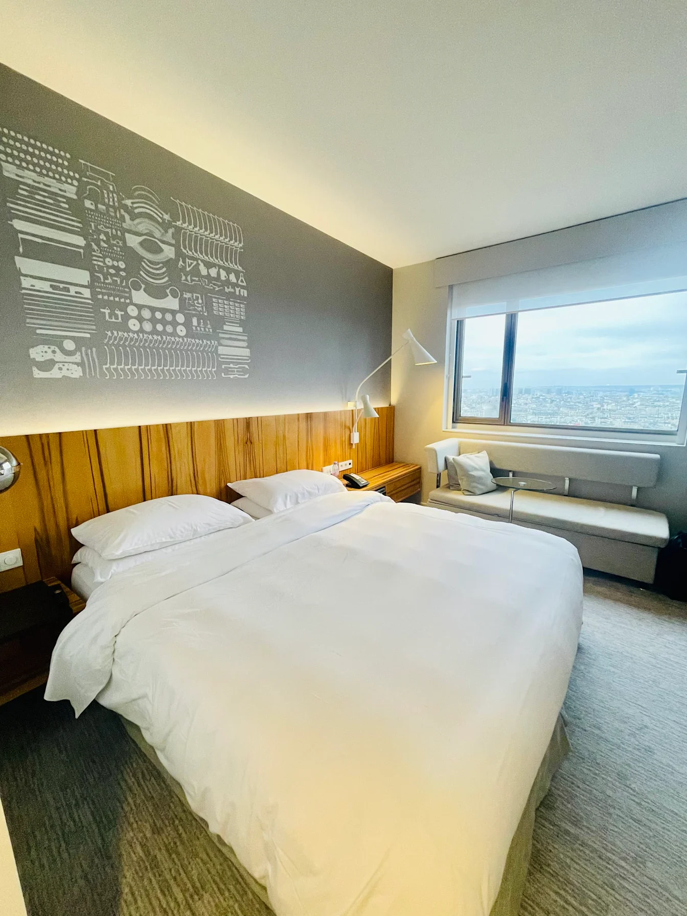 Giường King trong phòng King Deluxe, cạnh sofa và cửa sổ nhìn ra Paris
