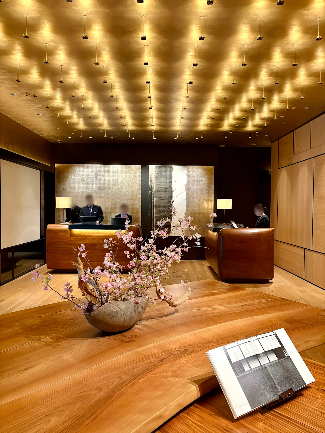 Quầy lễ tân Park Hyatt Kyoto với trần đèn và bình hoa anh đào