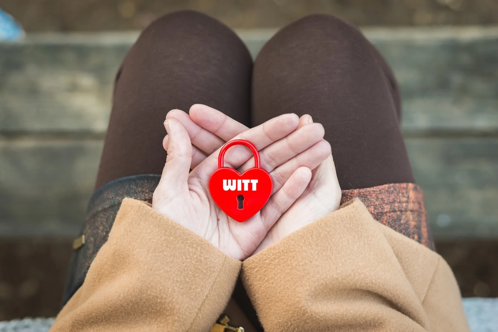 Rode hartvormige hangslot met de tekst 'WITT', vastgehouden in twee handen.