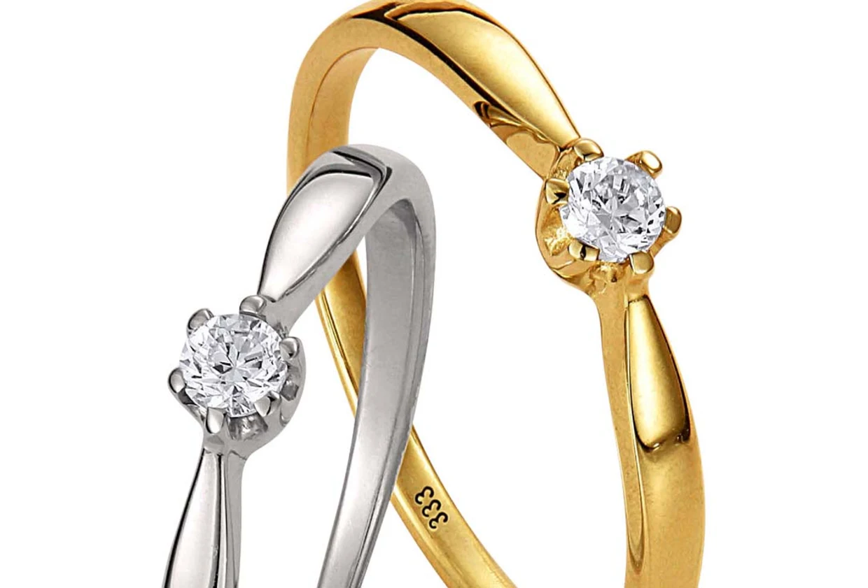 Zwei Verlobungsringe, einer aus Silber und einer aus Gold, beide mit einem einzelnen glitzernden Diamanten besetzt.