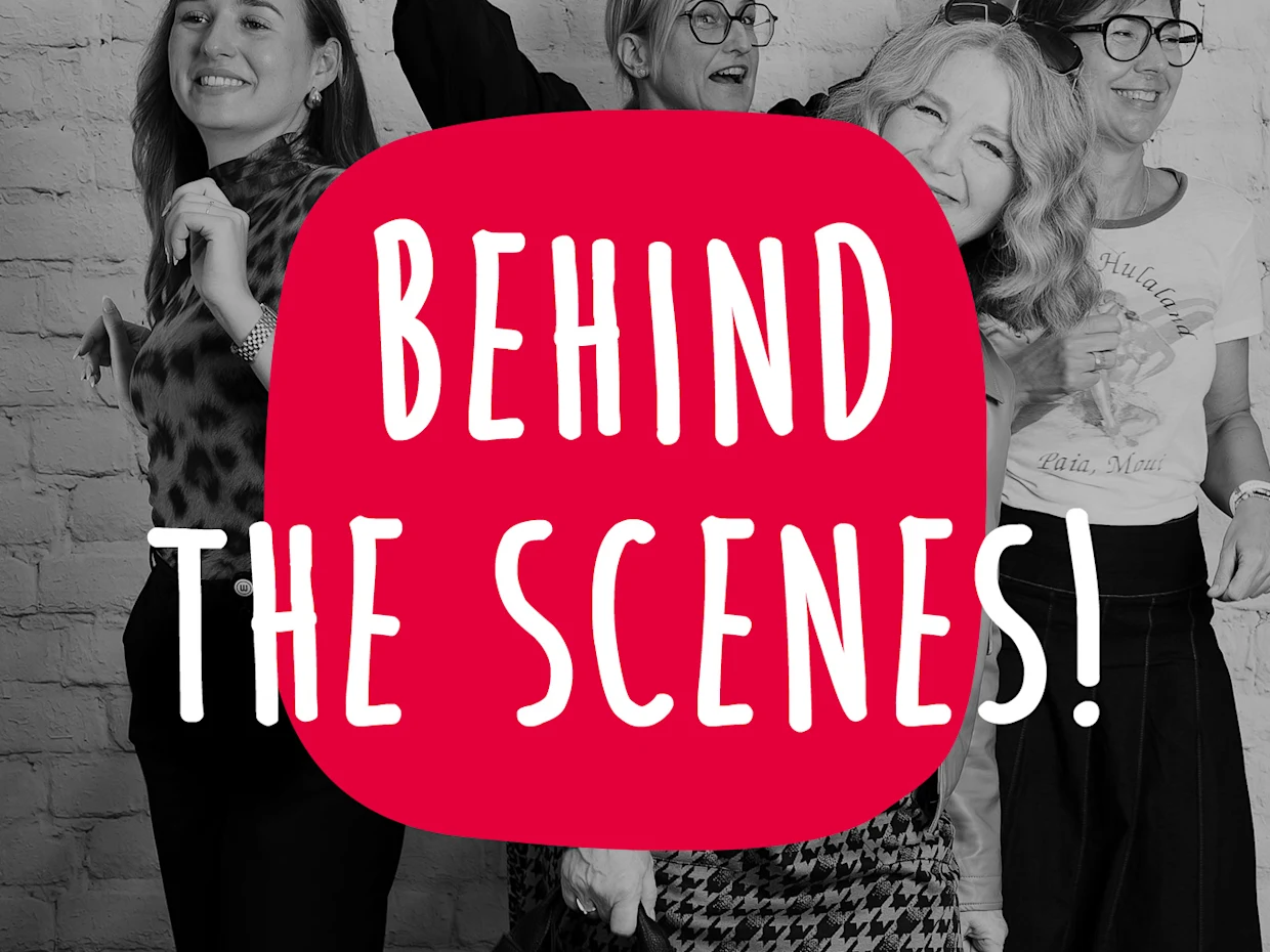 Eine Schwarz-Weiß-Aufnahme, die eine Gruppe lachender Frauen zeigt, mit einem großen roten Kreis in der Mitte, auf dem in weißen Großbuchstaben „BEHIND THE SCENES!“ steht. Eine Schwarz-Weiß-Aufnahme, die eine Gruppe lachender Frauen zeigt, mit einem großen roten Kreis in der Mitte, auf dem in weißen Großbuchstaben „BEHIND THE SCENES!“ steht.