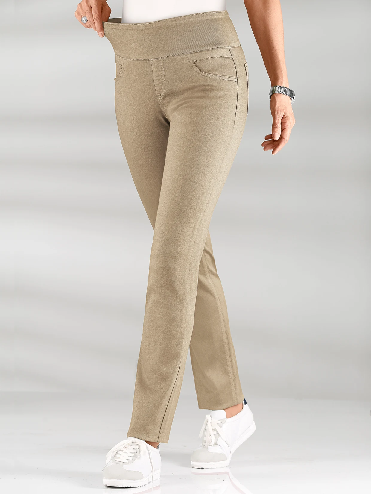 Damenhose in Beige mit elastischem Bund, schmaler Passform und weißen Sneakern kombiniert. Damenhose in Beige mit elastischem Bund, schmaler Passform und weißen Sneakern kombiniert.