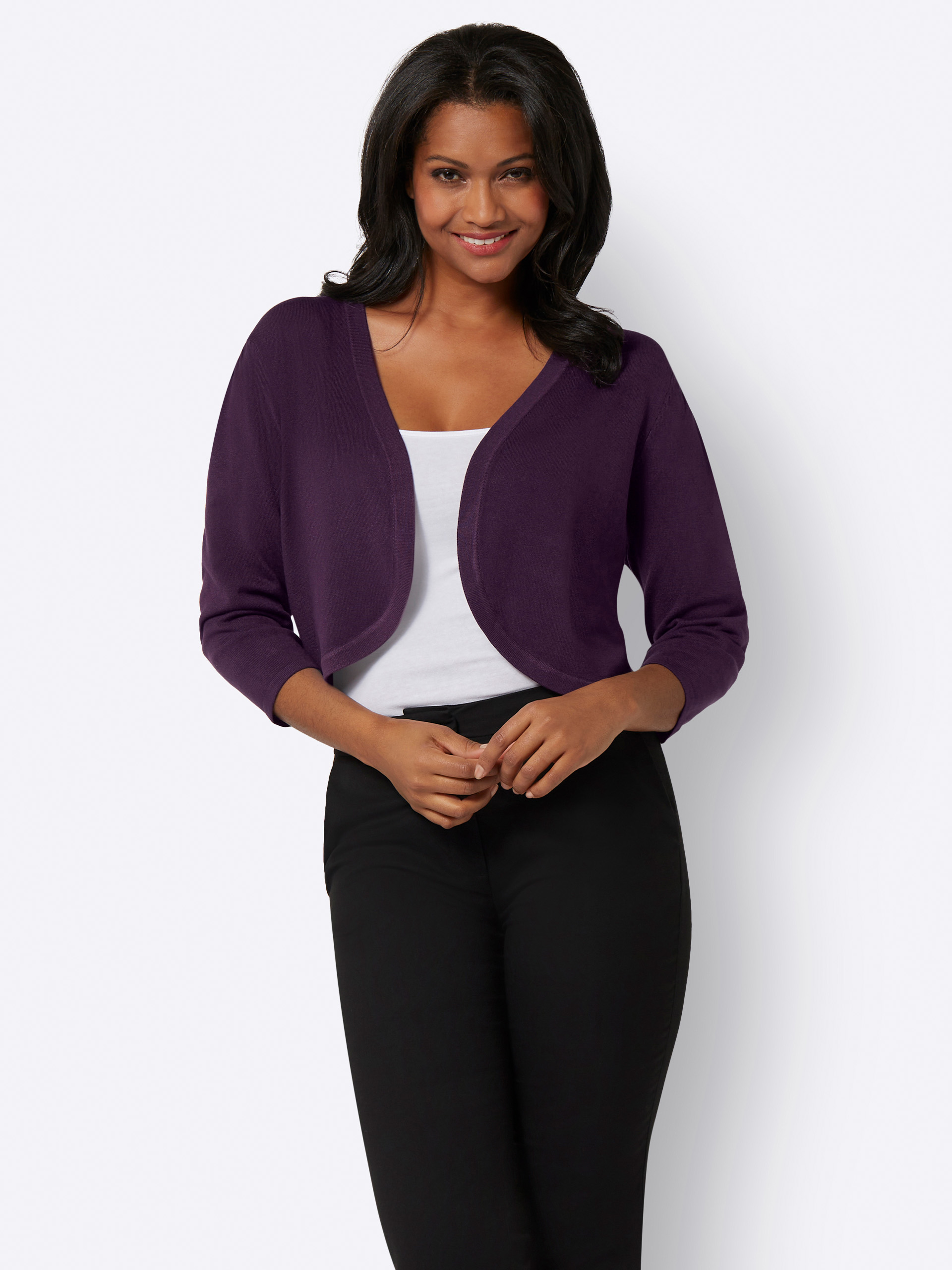 Frau trägt einen eleganten, lila Bolero mit 3/4-Ärmeln über einem weißen Top, dazu eine schwarze Hose, vor neutralem Hintergrund.