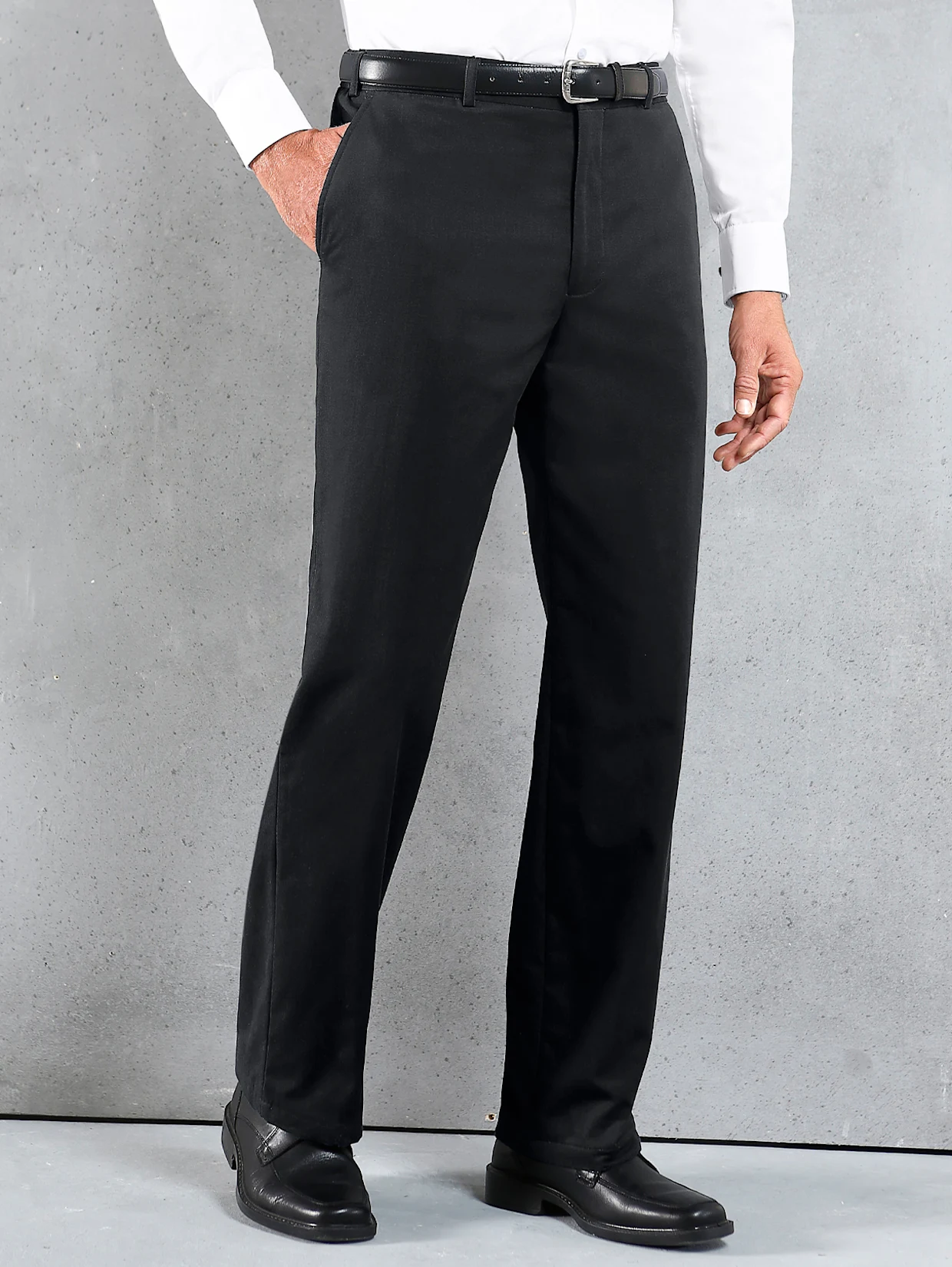 Elegante schwarze Herrenhose mit geradem Schnitt, kombiniert mit weißem Hemd, schwarzem Ledergürtel und schwarzen Lederschuhen vor grauem Hintergrund. Elegante schwarze Herrenhose mit geradem Schnitt, kombiniert mit weißem Hemd, schwarzem Ledergürtel und schwarzen Lederschuhen vor grauem Hintergrund.
