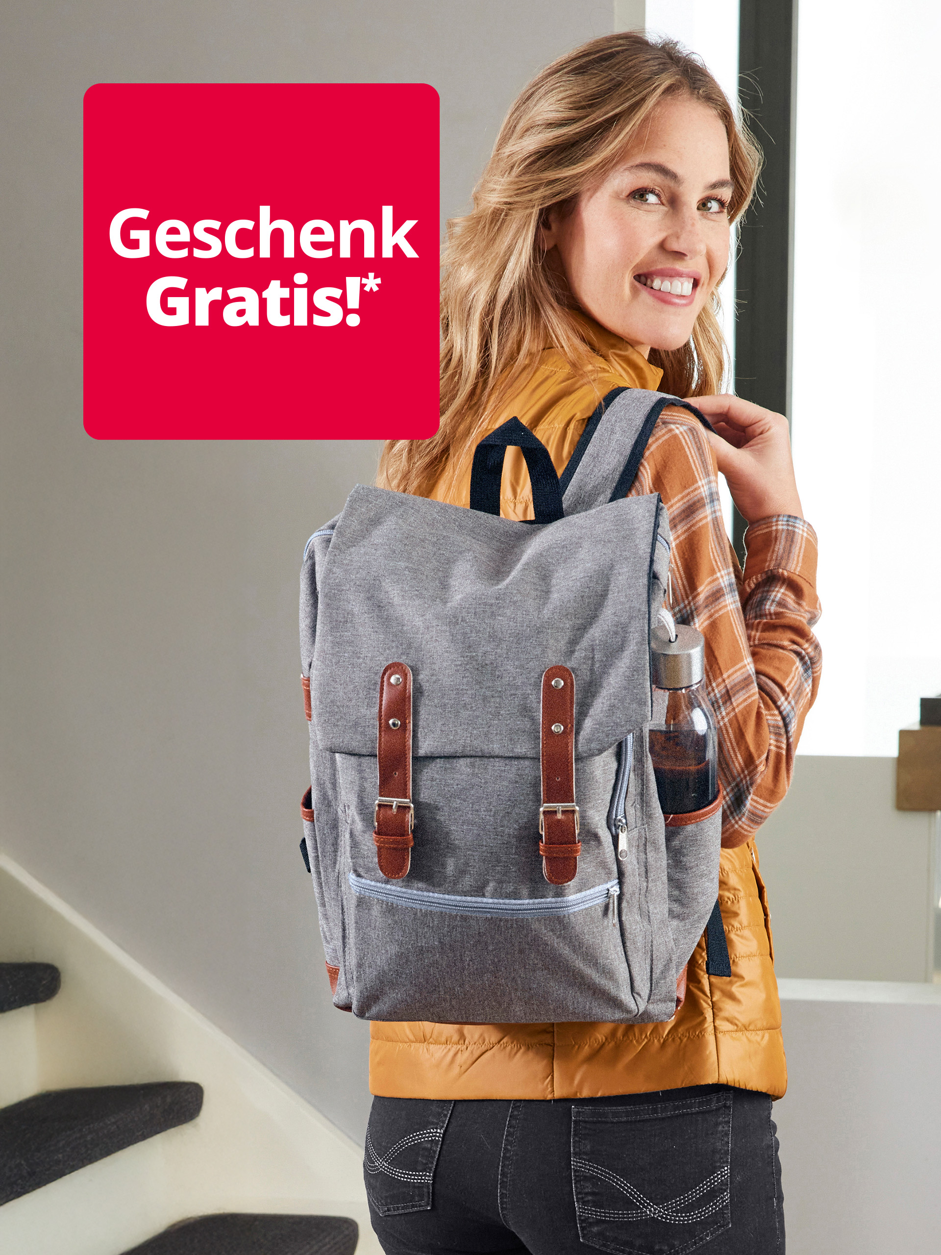 Eine lächelnde Frau mit einem grauen Rucksack und einer Wasserflasche im Seitenfach. Links oben ist ein rotes Quadrat mit der Aufschrift "Geschenk Gratis!*" zu sehen.