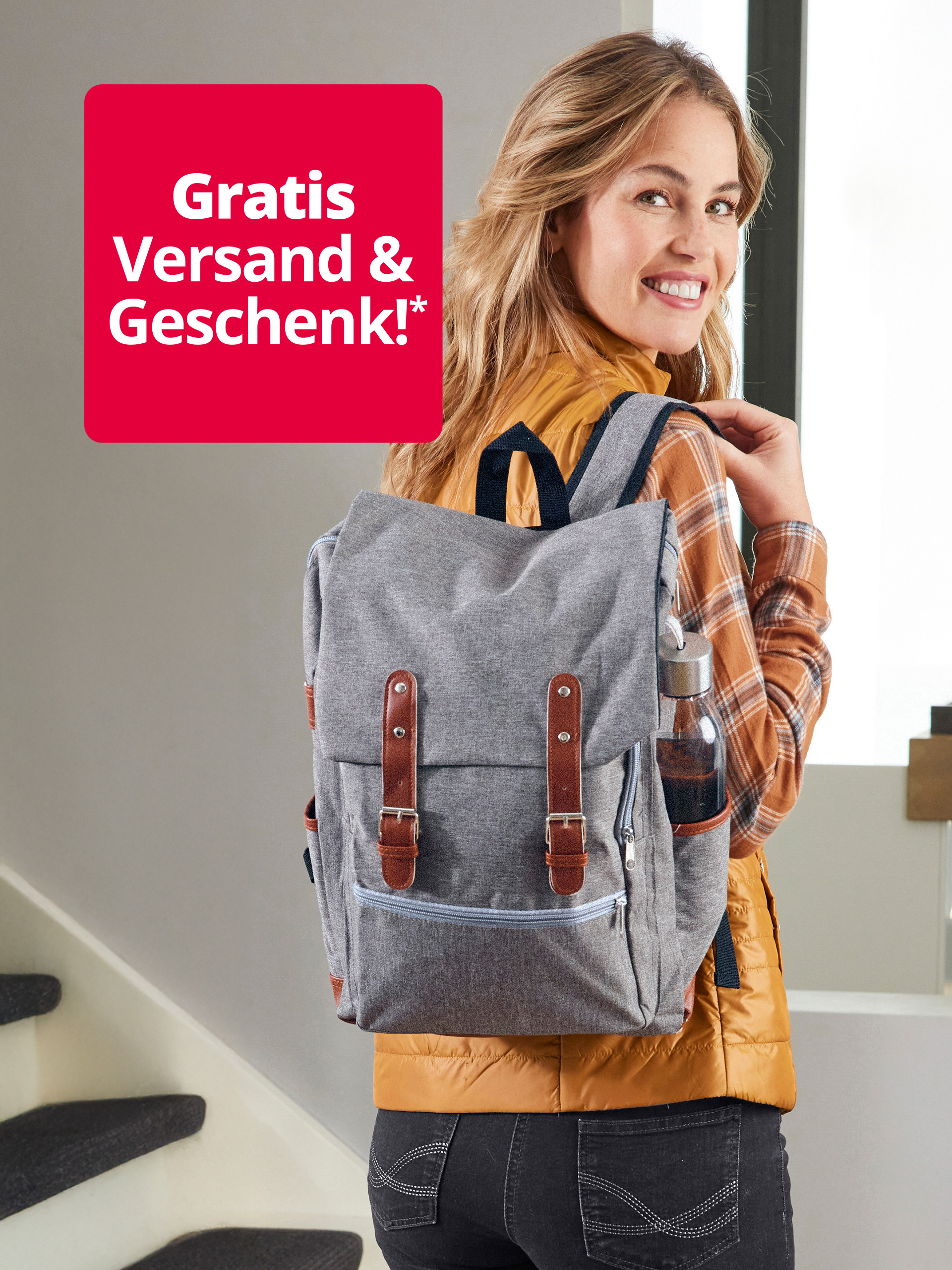 Eine lächelnde Frau mit einem grauen Rucksack und einer Wasserflasche im Seitenfach. Links oben ist ein rotes Quadrat mit der Aufschrift "Gratis Versand & Geschenk!*" zu sehen.