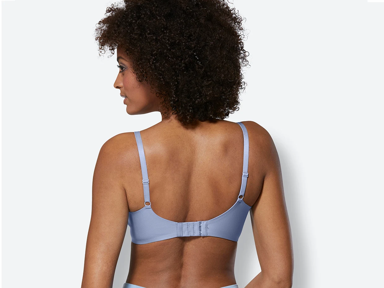 Rückansicht einer Frau mit einem hellblauen BH mit verstellbaren Trägern und Hakenverschluss auf weißem Hintergrund.