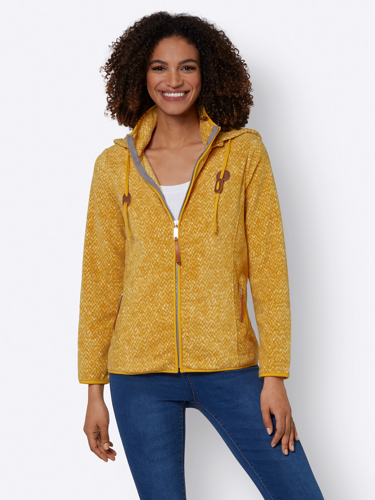 Gelbe Damen-Fleecejacke mit Reißverschluss, Kapuze und dekorativen Kordeln, kombiniert mit blauer Jeans.