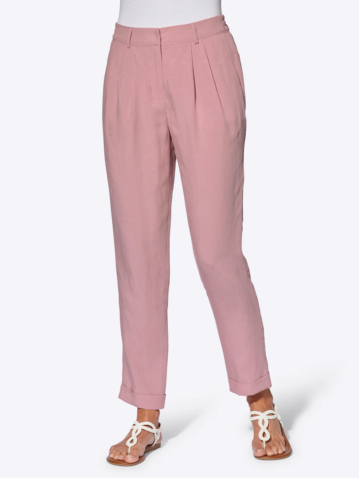 Rosa Damenhose aus leichtem Stoff mit Bundfalten, kombiniert mit weißen Sandalen. Rosa Damenhose aus leichtem Stoff mit Bundfalten, kombiniert mit weißen Sandalen.